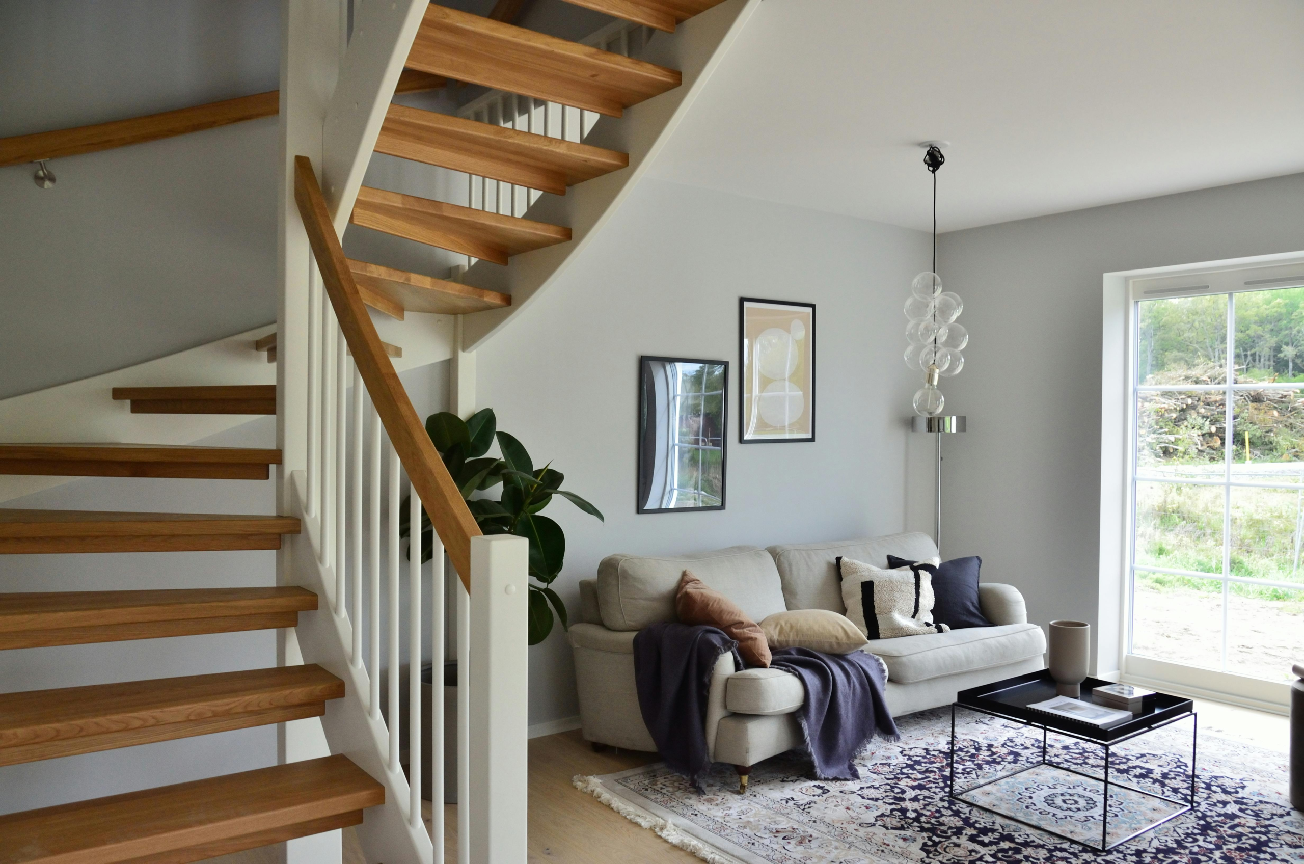 Stylish Scandinavian living room featuring a wooden staircase, cozy sofa, and modern decor.